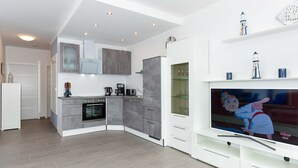 Una cocina moderna con armarios grises, horno empotrado y refrigerador blanco.