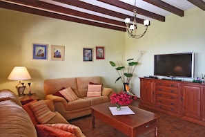 A living room with a sofa, a coffee table with a vase of flowers, a television, and a cabinet.