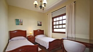 Un dormitorio con dos camas de madera, un escritorio y una silla.