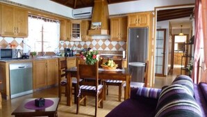 A compact kitchen with wooden cabinets, a dining table with chairs, and a purple sofa.