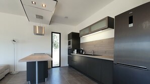 Une cuisine moderne avec des meubles de couleur sombre, un réfrigérateur en acier inoxydable et un four encastré.