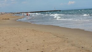 Une plage avec une digue rocheuse et un phare visible au loin.