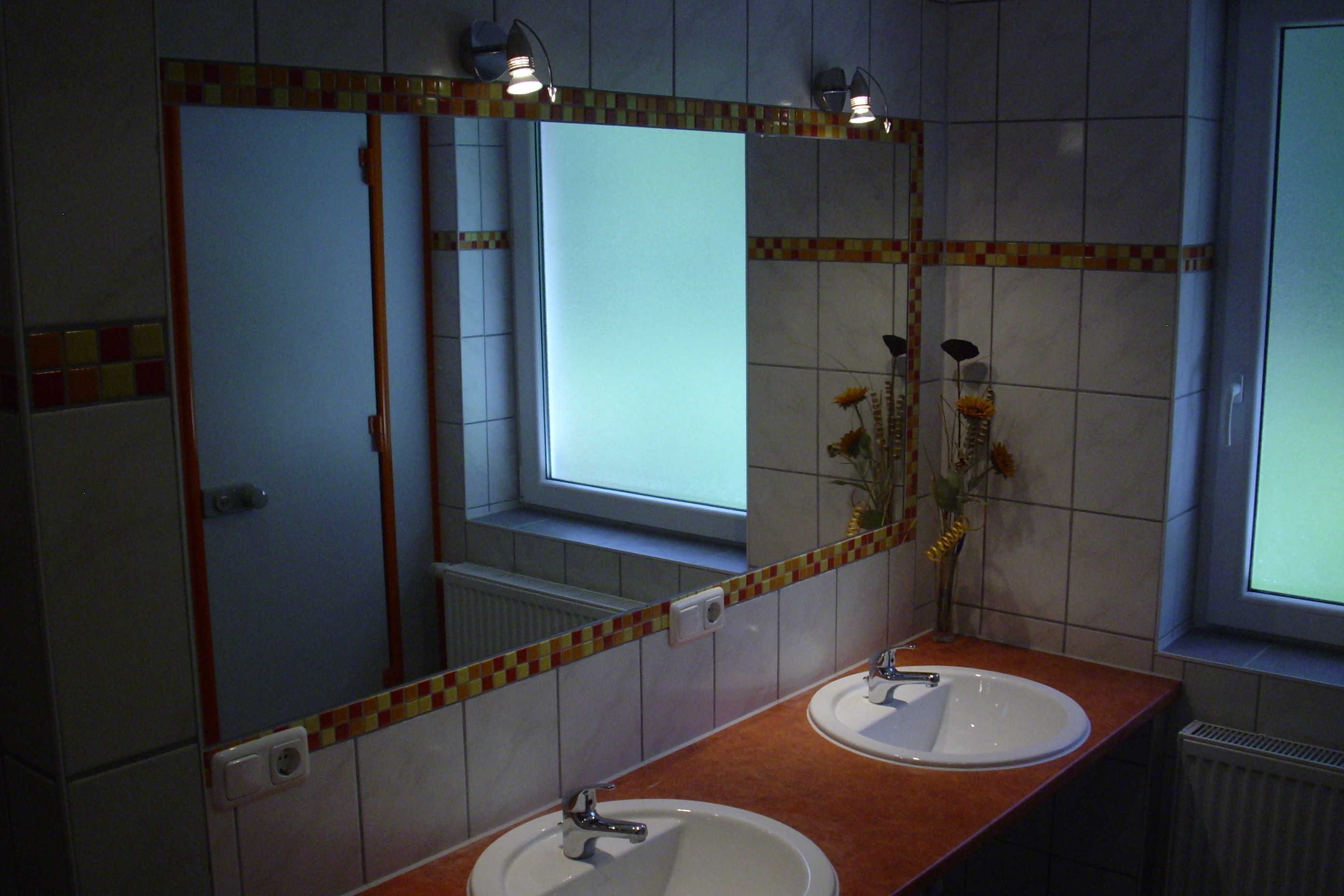 A bathroom with two sinks, a large mirror, and a window.