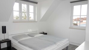 Makuuhuone, jossa on sänky, yöpöytä, lamppu ja ikkuna.