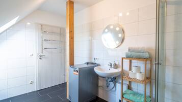 Ein modernes Badezimmer mit Dusche, Waschbecken, Spiegel und Handtuchhalter.