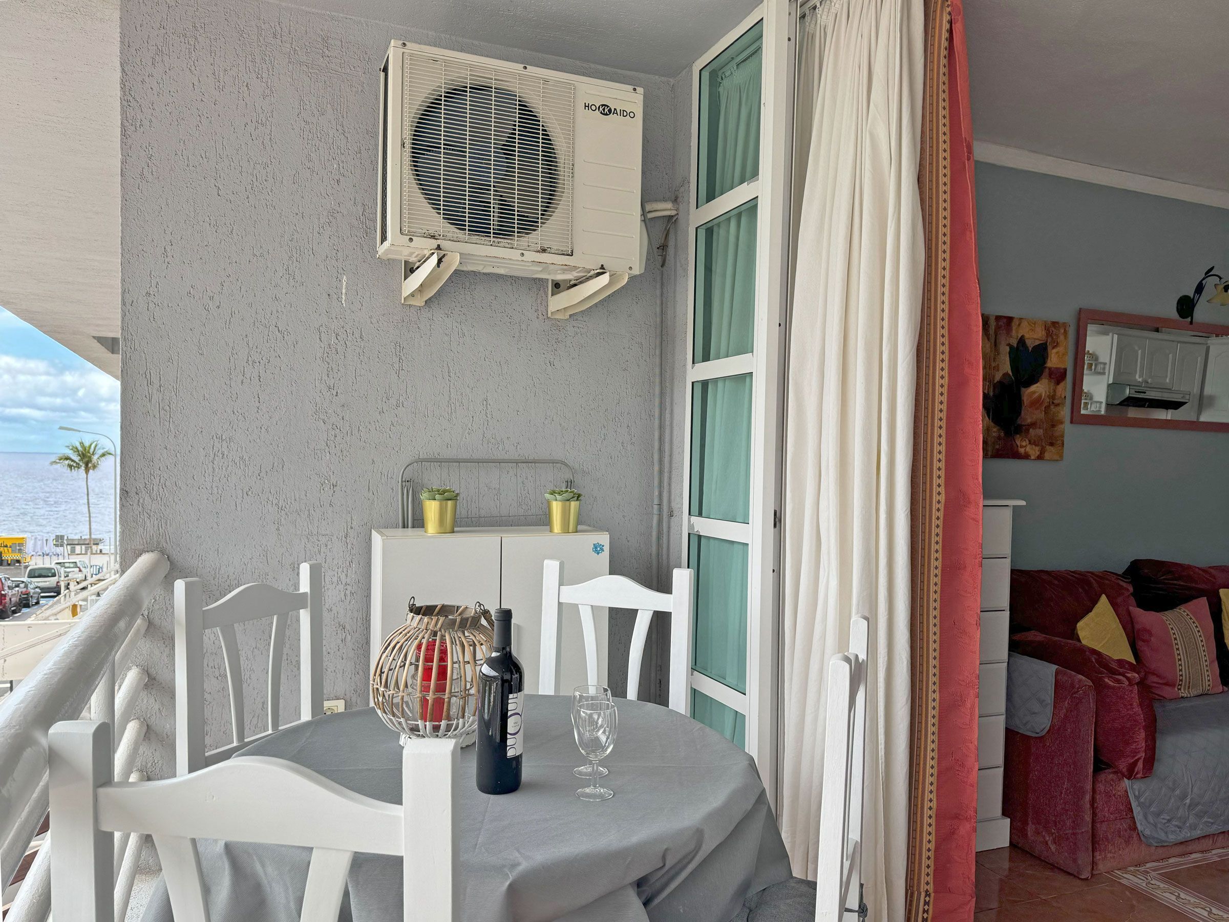 A balcony with a table, chairs, a bottle of wine, and a decorative item.