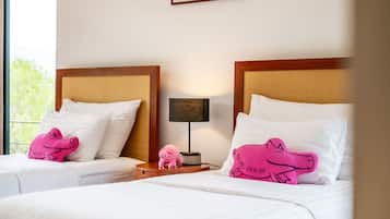 Duas camas com cabeceiras iguais, roupa de cama branca e almofadas em formato de porco rosa.
