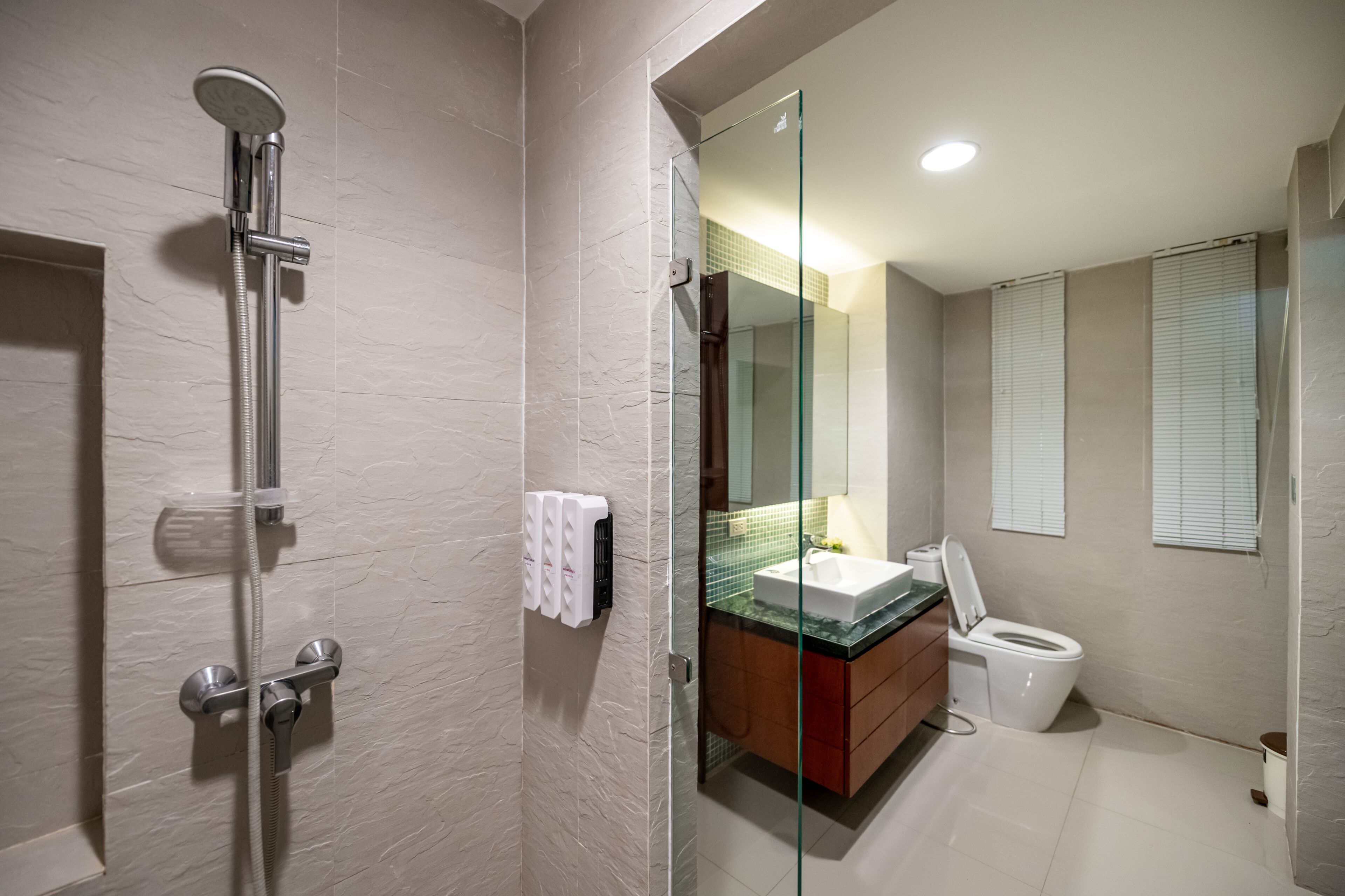 A modern bathroom with a glass-enclosed shower, a white sink, and a toilet.