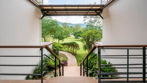 A staircase leading to a garden with a view of a green landscape and a clear sky. - The Pig House Khao Yai (Pak Chong)