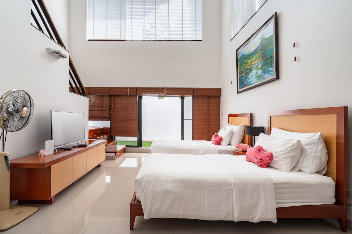 A modern hotel room with two beds, a desk, a TV, and a large window.