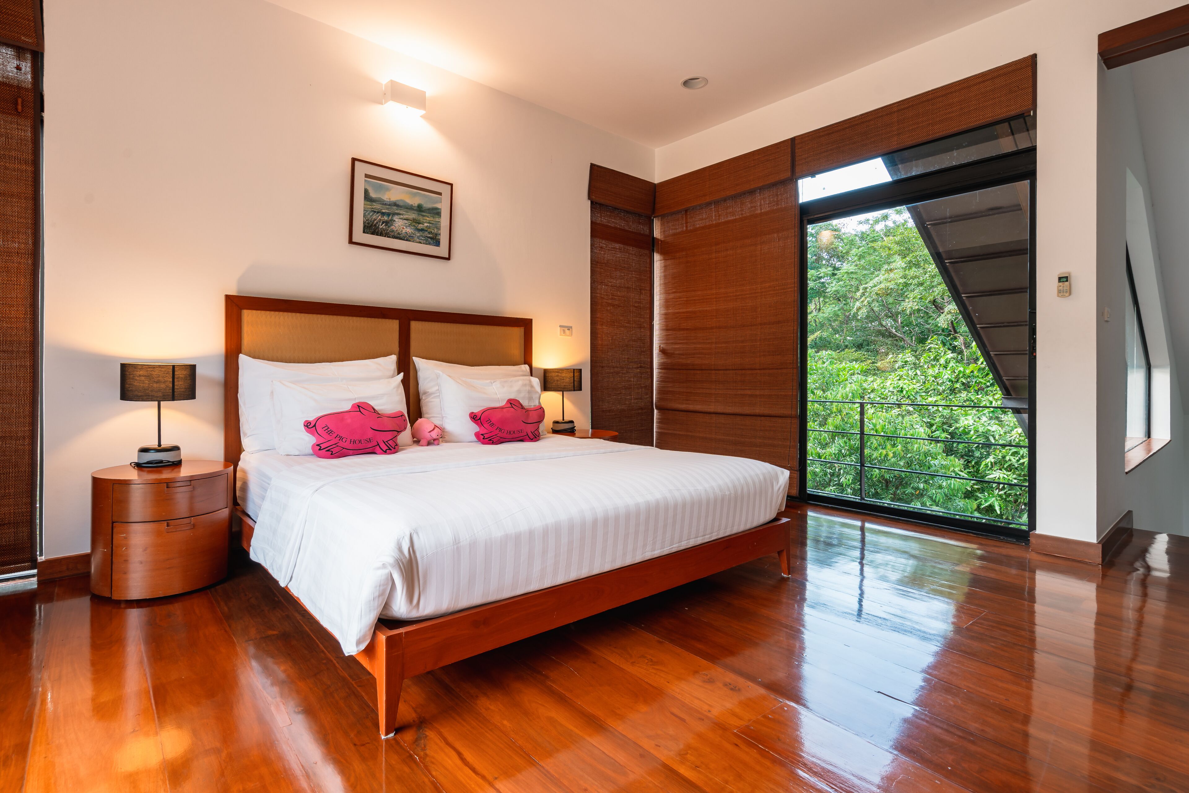 Un dormitorio con cama de madera, mesitas de noche, un cuadro y un ventanal con vistas a zonas verdes.