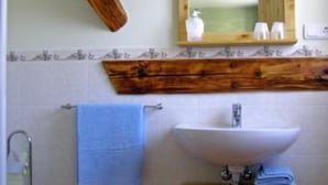 Ein Badezimmer mit einem Holzkonsolenunterschrank, einem weißen Waschbecken, einem Spiegel und einem blauen Handtuch.