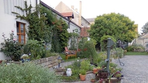 Ein Garten mit Topfpflanzen, einer hölzernen Bank und einem Pflasterweg.