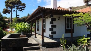 Ein kleines Haus mit Ziegeldach, Steinstufen und einem Garten mit verschiedenen Pflanzen.