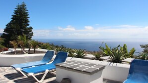 Eine Terrasse mit blauen Liegestühlen und Meerblick.