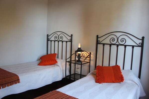Two single beds with black metal headboards, white bedding, and orange pillows. - Tres Pinos, Mazo, Spanien (Villa de Mazo)