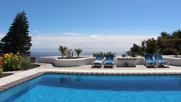 Ein Poolbereich mit Liegestühlen und Blick auf den Ozean.