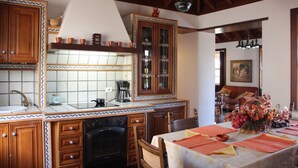 Eine Küche mit Holzausstattung, einer gefliesten Rückwand und einem Essbereich mit Tisch für zwei Personen.