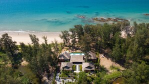 An aerial view of a coastal property with a beach, a swimming pool, and lush greenery. - The Pines (Takua Thung)