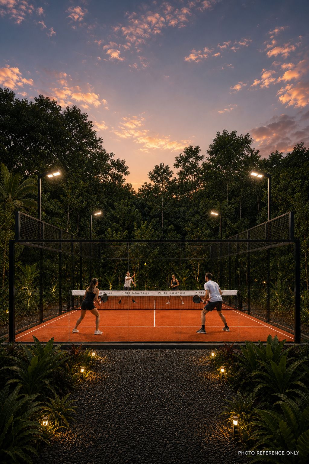An outdoor tennis court with players, surrounded by trees and illuminated by street lamps.