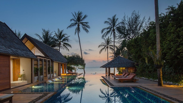 A infinity pool with a clear view of the ocean, surrounded by palm trees and a wooden building with a balcony. - Baan Puri (Koh Samui)