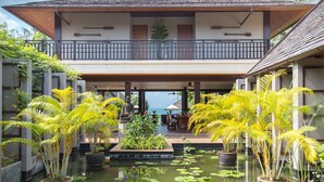 A resort with a covered outdoor area, a pool with water lilies, and a view of the ocean. - Baan Puri (Koh Samui)