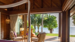 A room with a bed, two chairs, a table, and a view of the sea. - Baan Puri (Koh Samui)