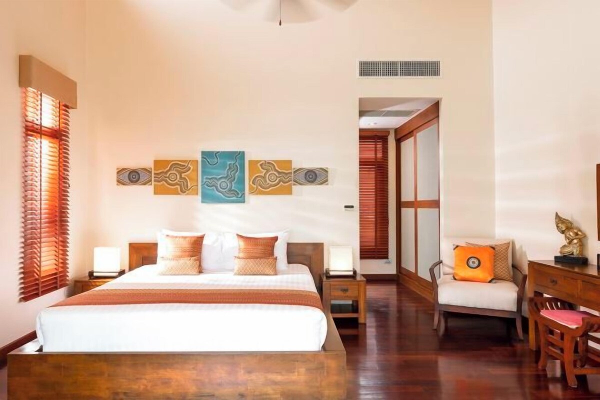 Um quarto com uma cama grande, mesas de cabeceira, uma cadeira e uma escrivaninha.