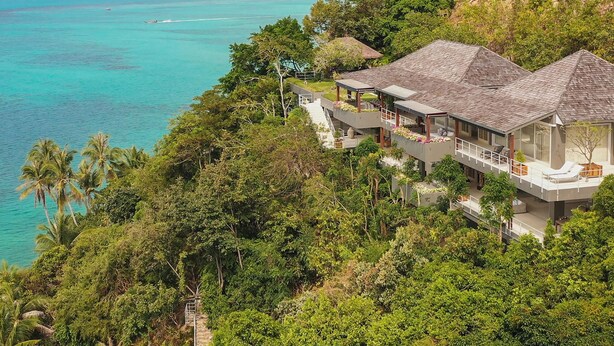A coastal property with a large house featuring multiple balconies, a staircase leading to the upper levels, and lush greenery surrounding the area. - Cape Laem Sor Estate (Koh Samui)