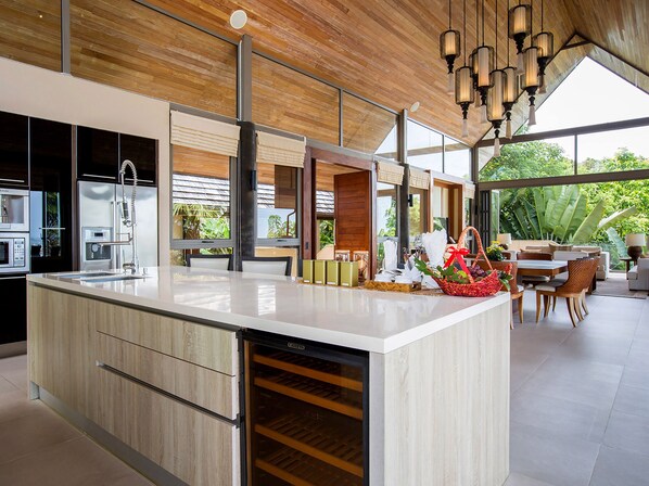 A modern kitchen with a large island, built-in appliances, and a dining area with a view of the outdoors.