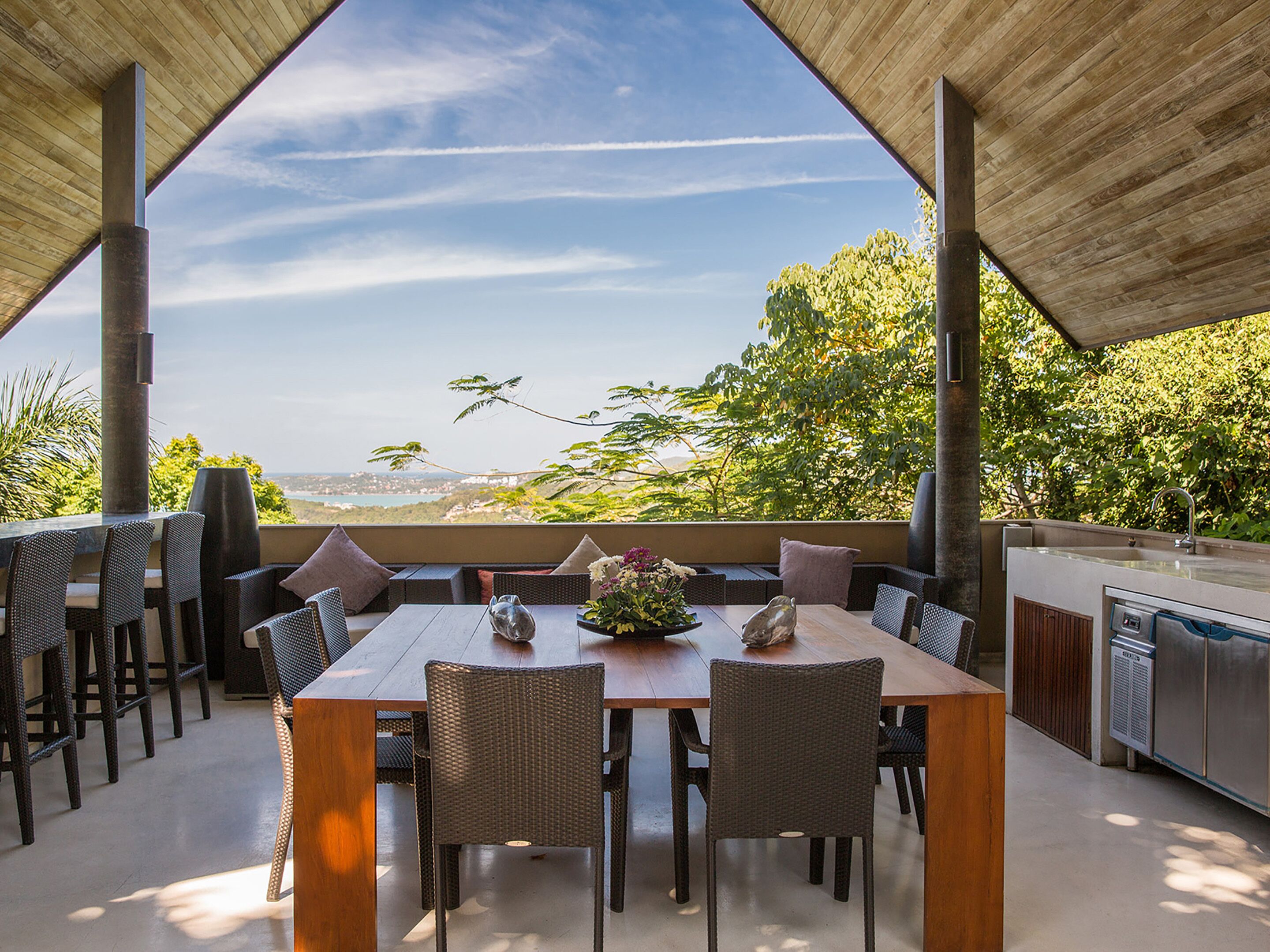 An outdoor dining area with a view of the landscape, a table with chairs, and a grill.