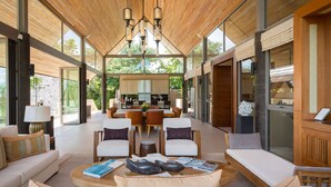 A spacious living area with a wooden ceiling, a central dining table, and a sofa set. - Panacea Retreat (Koh Samui)