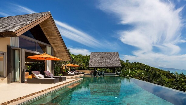A modern infinity pool with clear water, lounge chairs, and umbrellas. - Panacea Retreat (Koh Samui)