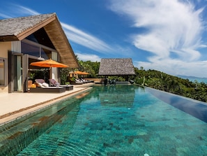A modern infinity pool with clear water, lounge chairs, and umbrellas.