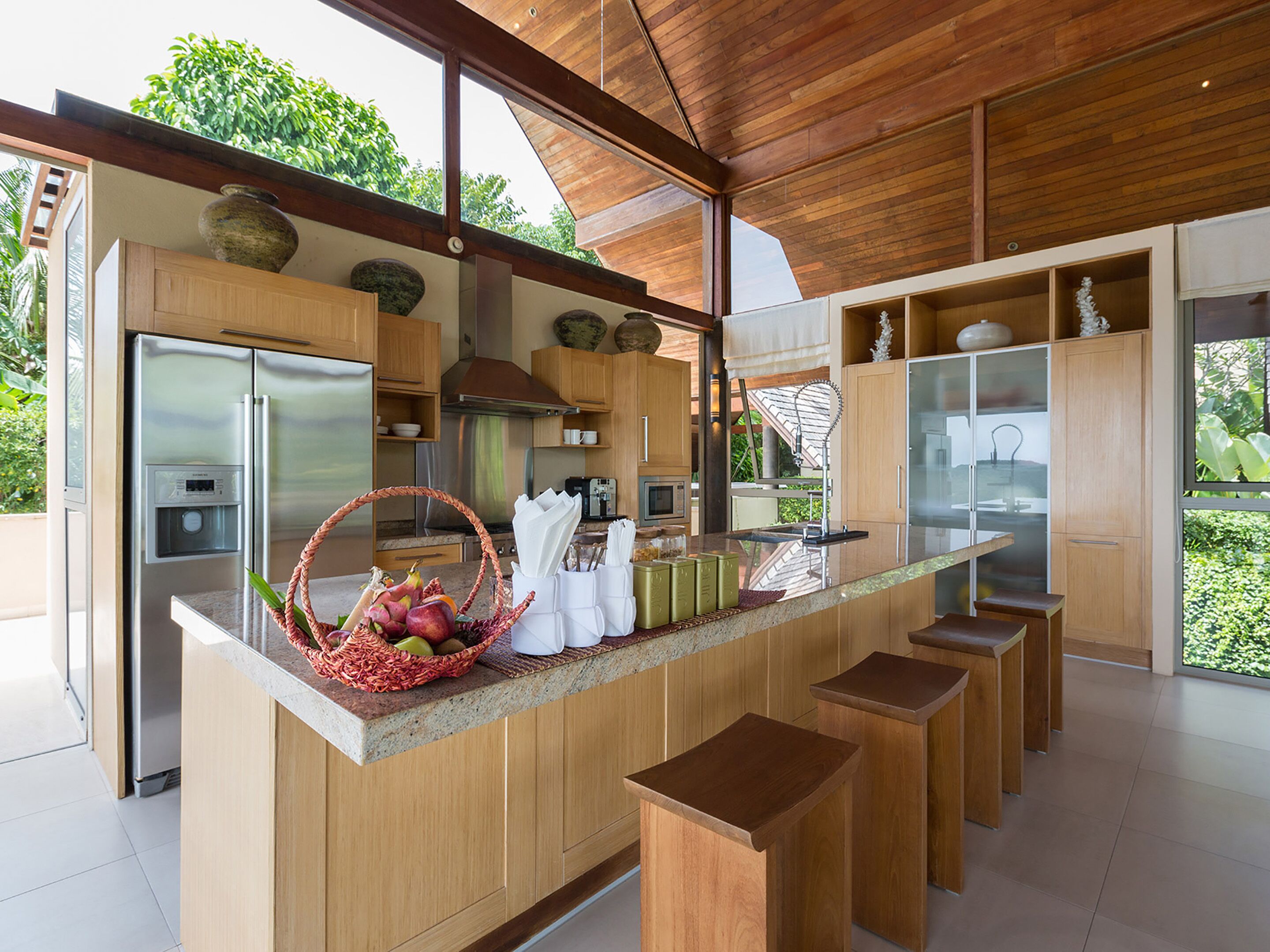 Una cocina moderna con armarios de madera, una isla central con taburetes y vistas a zonas verdes.