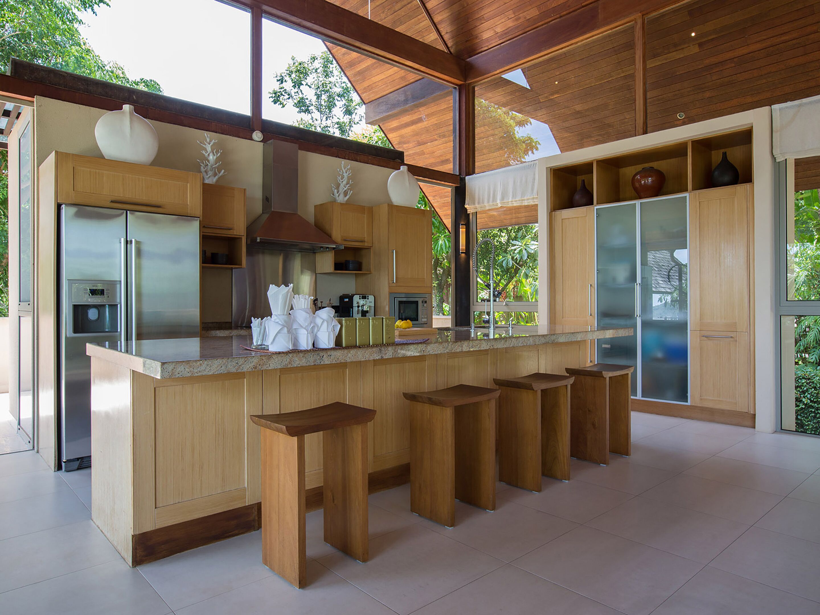 Una cocina moderna con armarios de madera, un refrigerador de acero inoxidable y una isla grande con taburetes de bar.