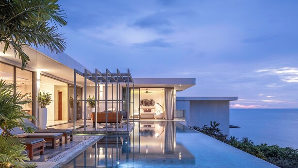 Ein modernes Haus mit Pool, Sitzgelegenheiten im Freien und Blick auf den Ozean.