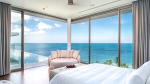 Ein geräumiges Schlafzimmer mit einem großen Bett, einer Sitzecke mit Meerblick und einem Balkon mit Blick auf das Meer.