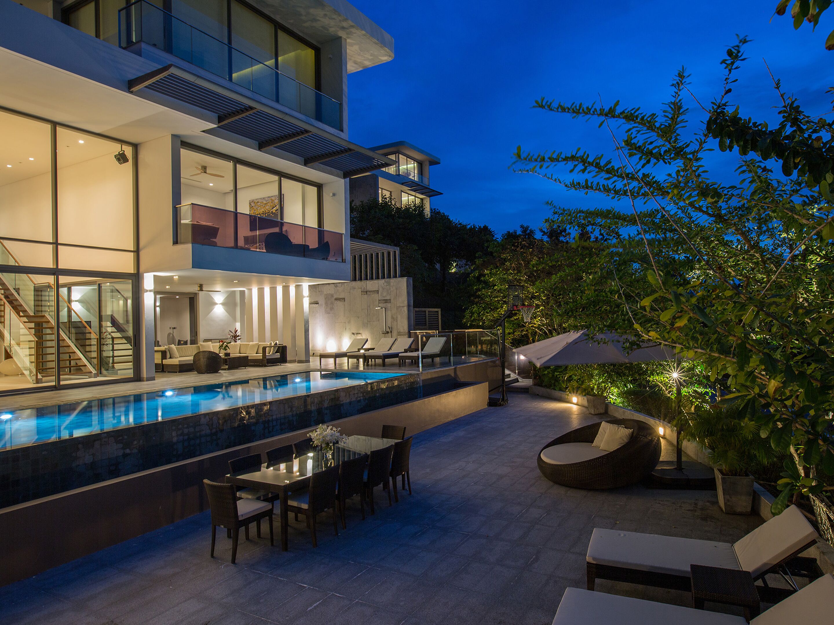 A modern two-story house with a swimming pool, outdoor seating, and a staircase leading to the upper floor.