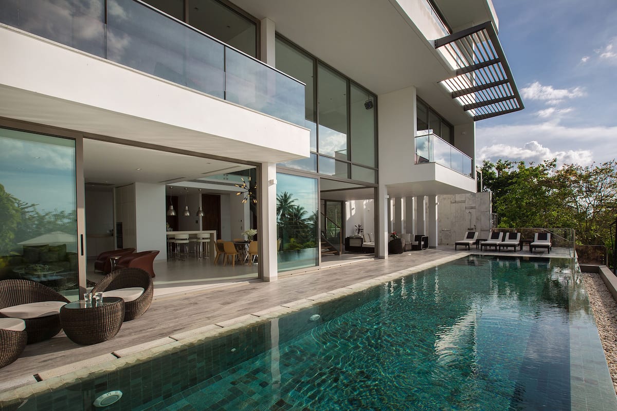 A modern house with a swimming pool, outdoor seating, and a dining area.