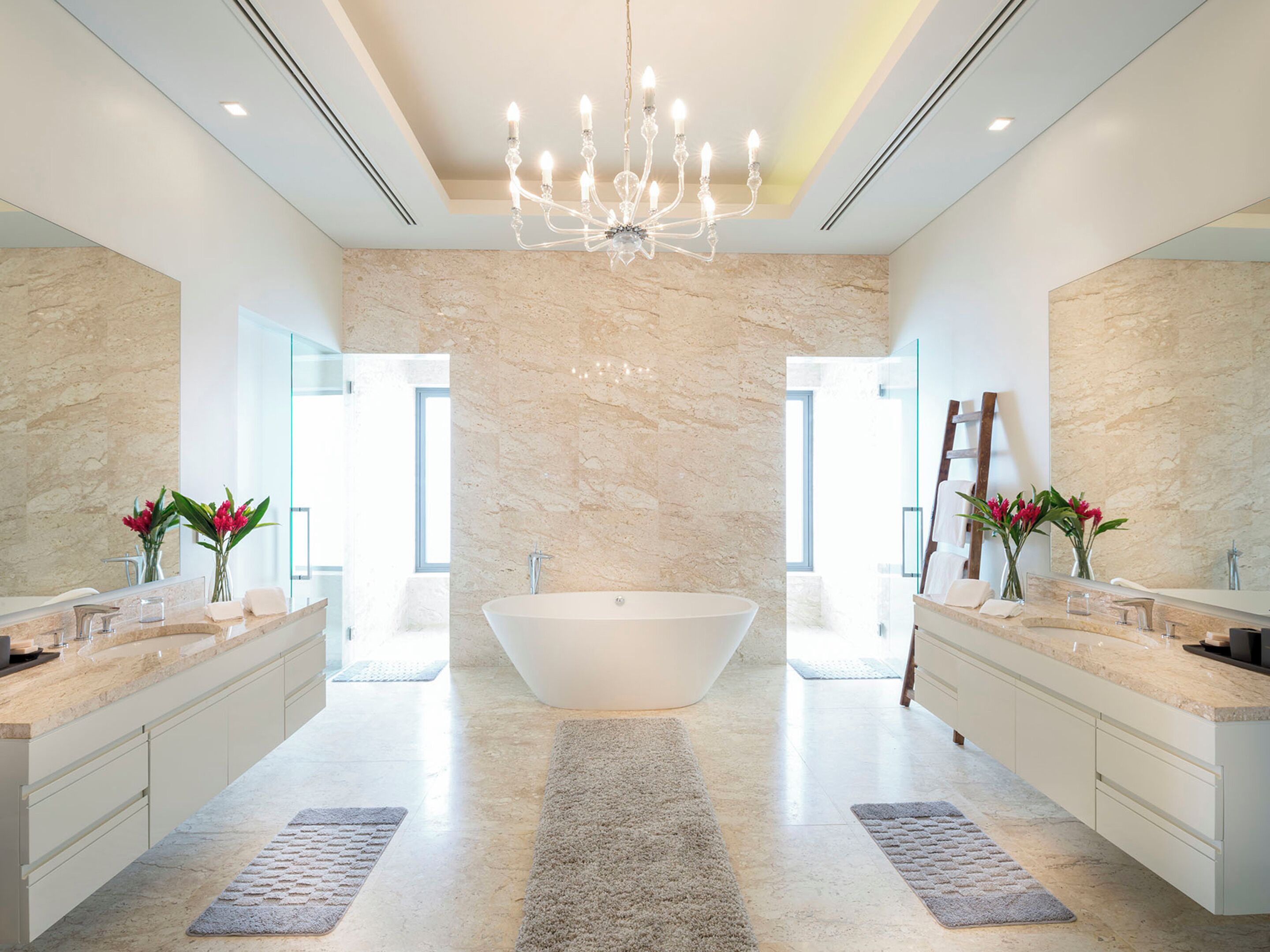 A spacious bathroom with a freestanding bathtub, two sinks, and a large mirror.