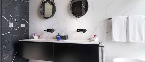 A modern bathroom with a black and white checkered floor, a black vanity with two sinks, a white bathtub, and two wall-mounted mirrors.