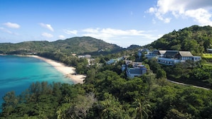 Ein Küstenresort mit Strandvillen, üppiger Vegetation und freiem Blick auf das Meer.