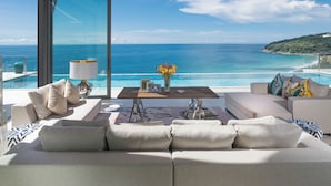 Ein modernes Wohnzimmer mit einem großen Fenster mit Blick auf einen Strand und den Ozean.