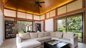 A modern living room with a sectional sofa, a coffee table, and a bookshelf. - Jivana Beach Villas (Takua Thung)