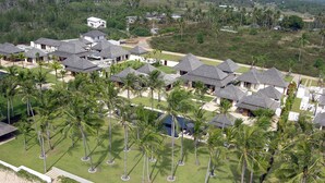 An aerial view of a resort with multiple bungalow-style buildings, a central swimming pool, and a beachfront. - Jivana Beach Villas (Takua Thung)