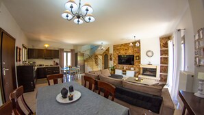 A spacious living area with a dining table, sofas, and a kitchen in the background. - Giannakis Villa (Kerkyra)