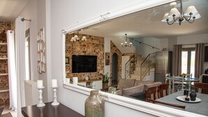 A dining area with a large mirror, a stone wall, and a staircase leading to another level. - Giannakis Villa (Kerkyra)