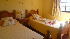A room with two beds, a nightstand with a lamp, and a window with curtains. - Apartment Rosa 1 - Apartments Rosa (Tijarafe)