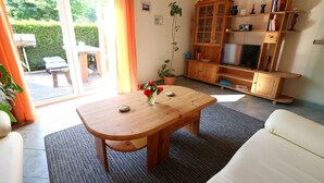 Un salon avec une table en bois, un canapé, un meuble avec des étagères et un téléviseur.